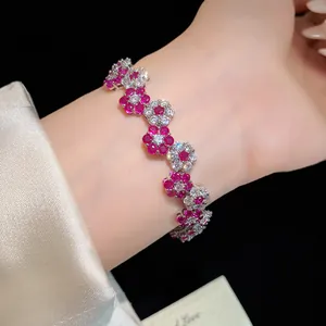 Close-up detail of silver bracelet featuring pink and white zircon flower charms