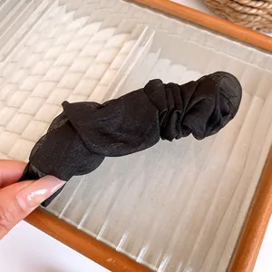 Close-up of the elegant pleated black fabric texture on a vertical banana hair clip