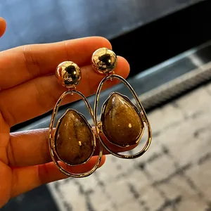 A close-up view of vintage water drop statement earrings featuring gold and brown resin details