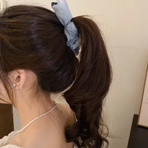 Close-up detail of a grey ruffled fabric banana hair clip styled in a high ponytail hairstyle