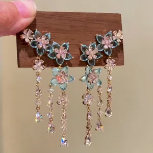 Close-up of blue zircon flower earrings with elegant tassels and gold chains