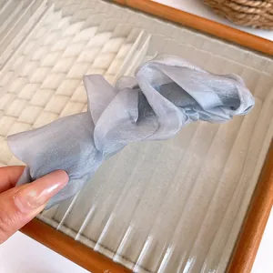 Close-up detail of a pleated silver grey fabric vertical banana hair clip for high ponytail
