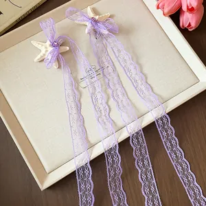 Dettaglio delle nappe di pizzo viola e delle clip per capelli a forma di stella marina.