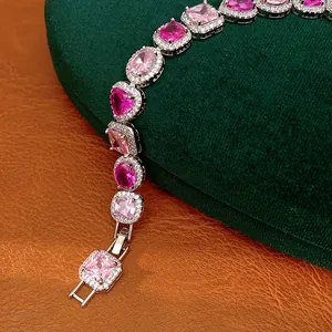 Detailed view of a luxury bracelet with pink heart and oval zircons on green velvet.