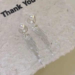 Dettaglio di eleganti orecchini a clip argentati con nappe lunghe e perle bianche