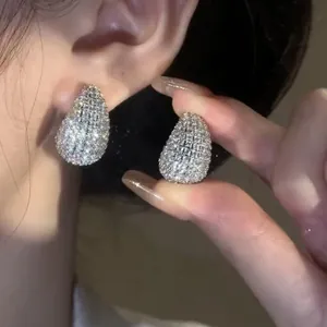 Close-up of sparkling French retro zircon water drop stud earrings shown on ear and hand