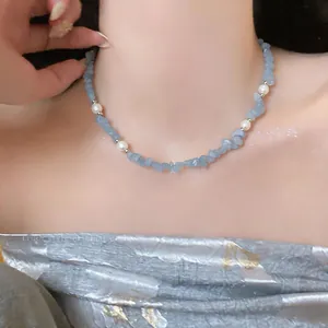 Detailed close-up of a handmade blue stone chip and white pearl beaded necklace on neck