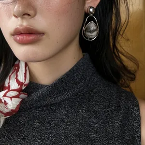 Close-up of vintage silver teardrop earrings with marble pattern stone on a model.