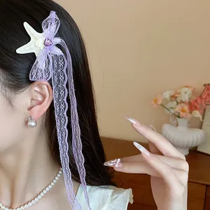 Dettaglio di un fermaglio per capelli con fiocco in pizzo viola e stella marina
