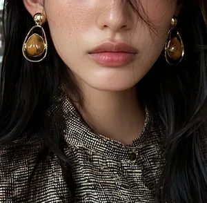 Detailed close-up of vintage gold drop earrings with amber stone texture worn by model