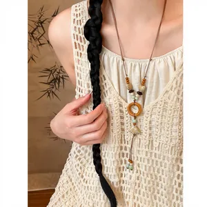 Close-up detail of ethnic wood and shell pendant necklace worn on cream crochet top