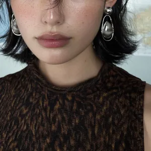 Close-up shot of vintage silver water drop pendant earrings worn by a female model