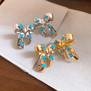 Elegant bow stud earrings with turquoise flower clusters in gold and silver finish.