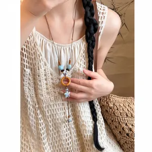 Detailed view of an ethnic style leather cord necklace featuring ceramic and wood elements
