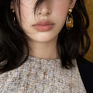 Close-up view of vintage golden drop earrings with amber stone worn by an Asian model