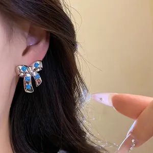 Elegant silver-plated bow stud earrings featuring delicate blue floral zircon accents