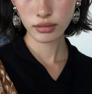 High-quality close-up of vintage silver waterdrop pendant earrings worn by a fashion model