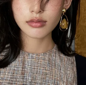 Detail view of retro water-drop gold earrings with natural stone texture on model