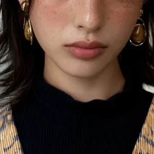 Close-up of vintage water drop earrings with unique brown stone texture on a model