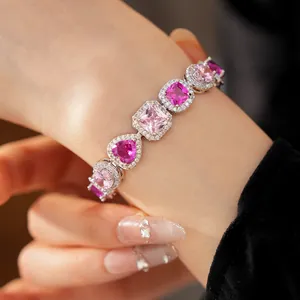 Close-up detail of a silver heart and square pink zircon bracelet on a woman's wrist