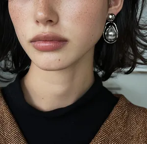 Detailed macro view of vintage silver waterdrop pendant earrings worn by a model.