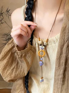 Detail view of ethnic style necklace with wooden ring and purple shell charm on model