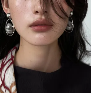 Close-up detail of a model wearing vintage silver teardrop earrings with marble stone