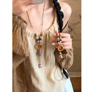Detail view of ethnic style necklace with wood rings, ceramic beads and shell charms