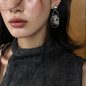 Close-up of a model wearing vintage silver teardrop pendant earrings with natural stone.