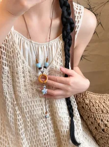 Close-up detail of ethnic style long necklace with ceramic beads and orange wooden ring