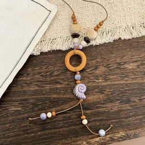Detail of ethnic style necklace with wooden ring and purple ceramic shell pendant