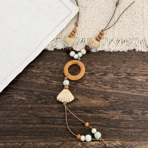 Close-up detail of ethnic style necklace featuring a ceramic shell and wooden ring accents