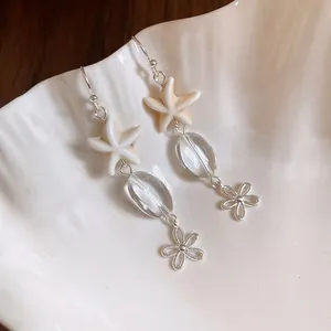 Close-up detail of beach-themed starfish earrings with clear glass beads and flower charms