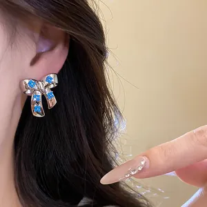 Elegant silver-tone bowknot stud earrings featuring dainty blue zircon flower details