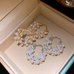 Close-up of elegant pearl and zirconia hoop earrings in gold and silver plating.