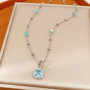 Elegant silver-tone necklace with square blue zircon pendant and glass beads.