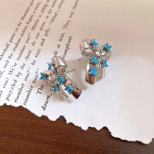 Detailed macro view of retro silver-tone bow earrings with blue floral stone patterns