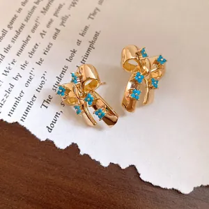 Detail view of vintage gold bowknot stud earrings with blue turquoise floral accents