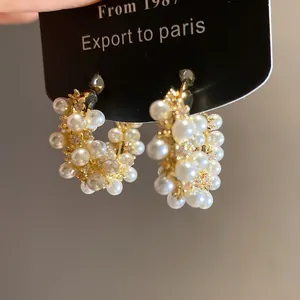Close-up of elegant 18k gold plated hoop earrings decorated with pearls and zircons.
