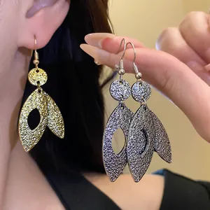 Detailed view of textured metal leaf drop earrings in elegant gold and silver finishes