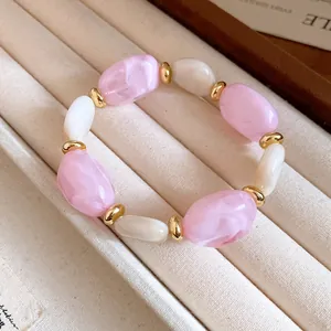 Nahaufnahme von rosa marmorierten Acrylperlen mit goldenen Zwischenstücken am Armband