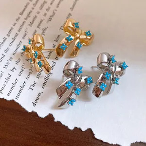 Macro view of retro silver needle bow stud earrings with turquoise flower details