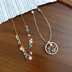 Detail view of a beaded flower necklace and a round stone woven pendant on wood