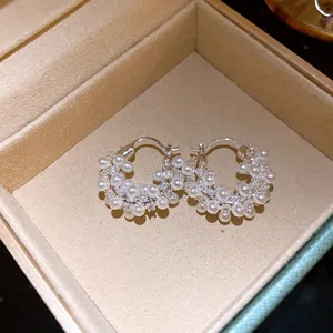Detailed macro view showing sparkling zircon and white pearls on elegant hoop earrings