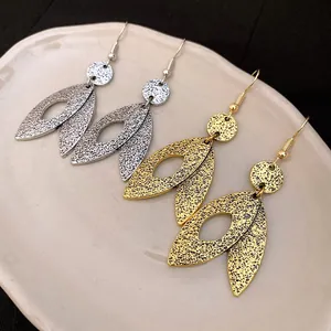 Detail view of stylish textured leaf-shaped dangle earrings in gold and silver.