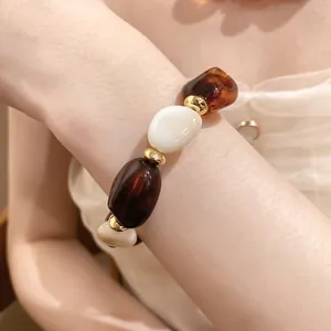 Nahaufnahme eines Vintage-Armbands mit unregelmäßigen bernstein- und cremefarbenen Acrylperlen