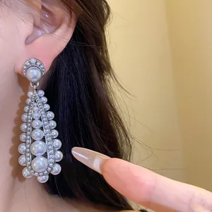Macro detail of vintage silver needle drop earrings with elegant white pearls.