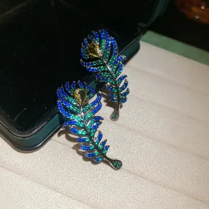 Detailed macro view of vintage peacock feather earrings inlaid with colorful sparkling zircon