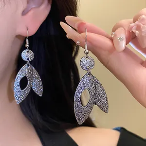 Detailed view of silver hammered textured leaf dangle earrings on a model's ear