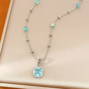 Detailed macro view of square blue crystal pendant with iridescent beaded silver chain necklace